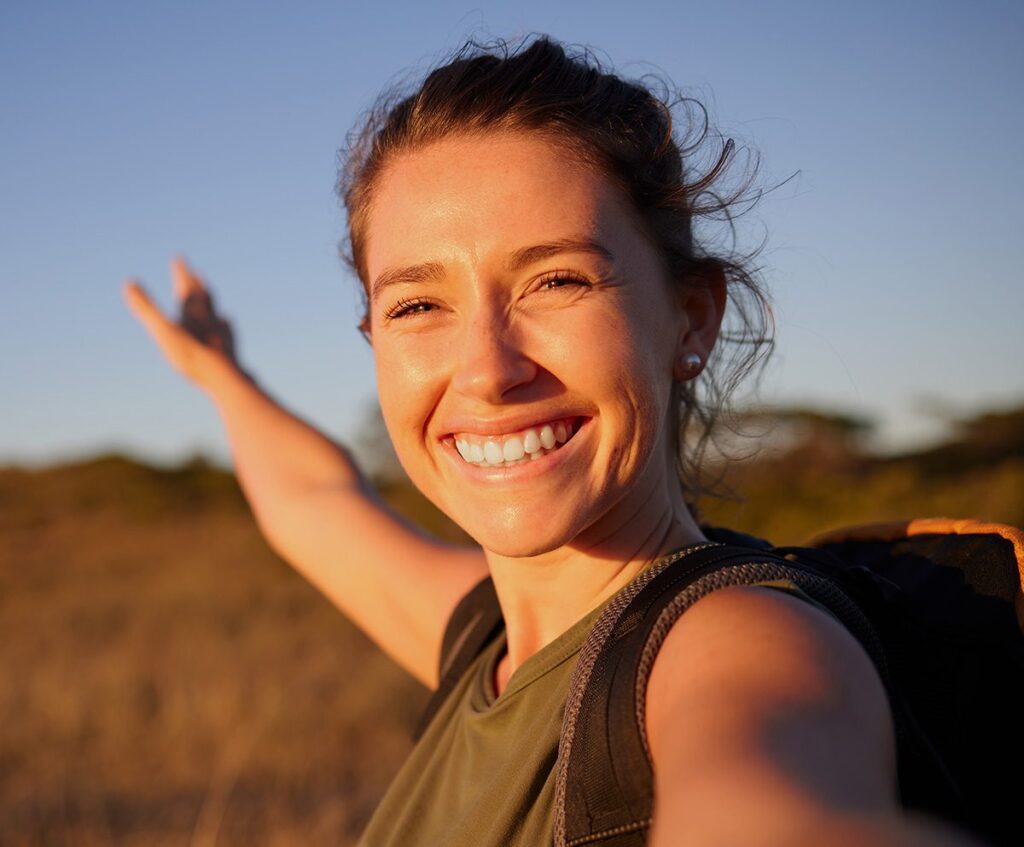 Women smiling outside with the sun shining on her